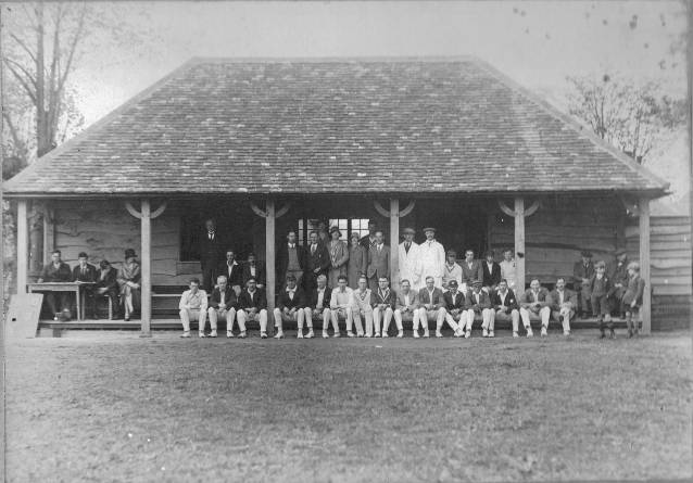 Two sets of players, umpires, spectators and scorers gather in front of the new clubhouse, taken shortly after its opening c.1930.Front row: Arthur Cutforth (second left), Harry Boatman (fifth left), Ernie Clarke (sixth left), Reg Salmon (eighth left). Maurice Kampe stands between Artur Cutforth and Harry Boatman.